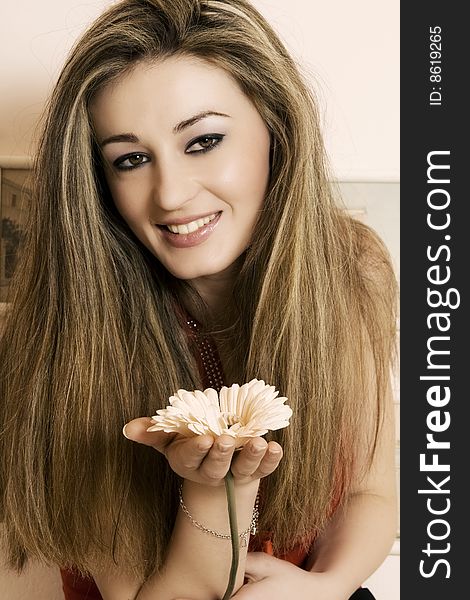 A beautiful young woman smiling holding a flower. A beautiful young woman smiling holding a flower