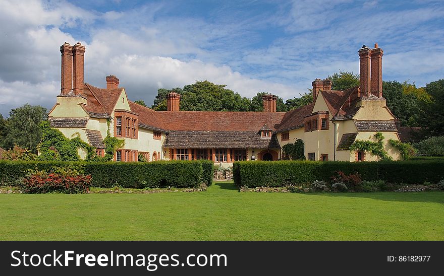 White And Brown Painted House Near Green Leafed Trees Under Sunny Blue Cloudy Sky