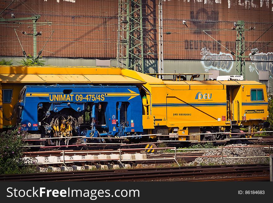 Railway locomotive engine in city, graffiti on brick building in background.