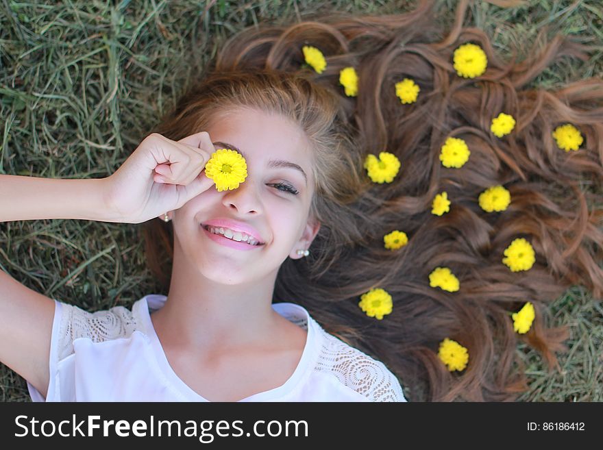 Portrait of teenage girl laying on ground with yellow flowers in long hair on green grass. Portrait of teenage girl laying on ground with yellow flowers in long hair on green grass.