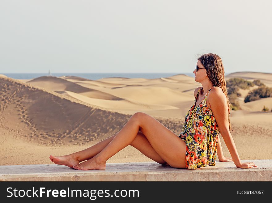 Woman Sitting on Sand at Beach Against Sky