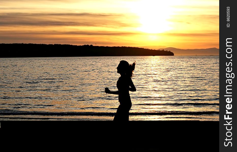 Silhouette of a female jogger at sunset.