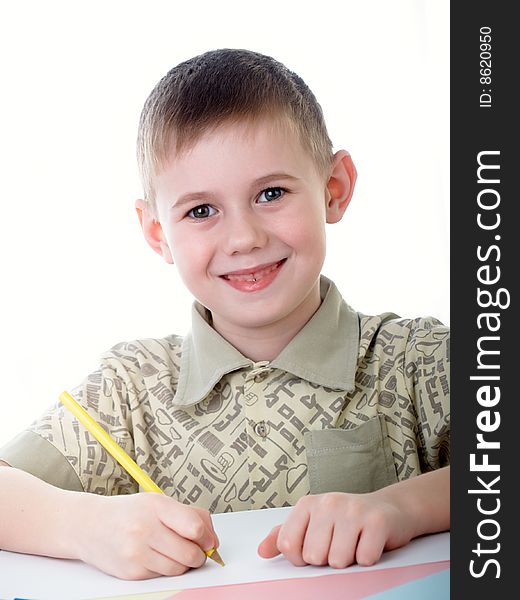 6 year old boy draws pencils sitting for a table. 6 year old boy draws pencils sitting for a table