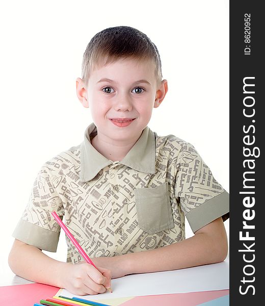 6 year old boy draws pencils sitting for a table. 6 year old boy draws pencils sitting for a table