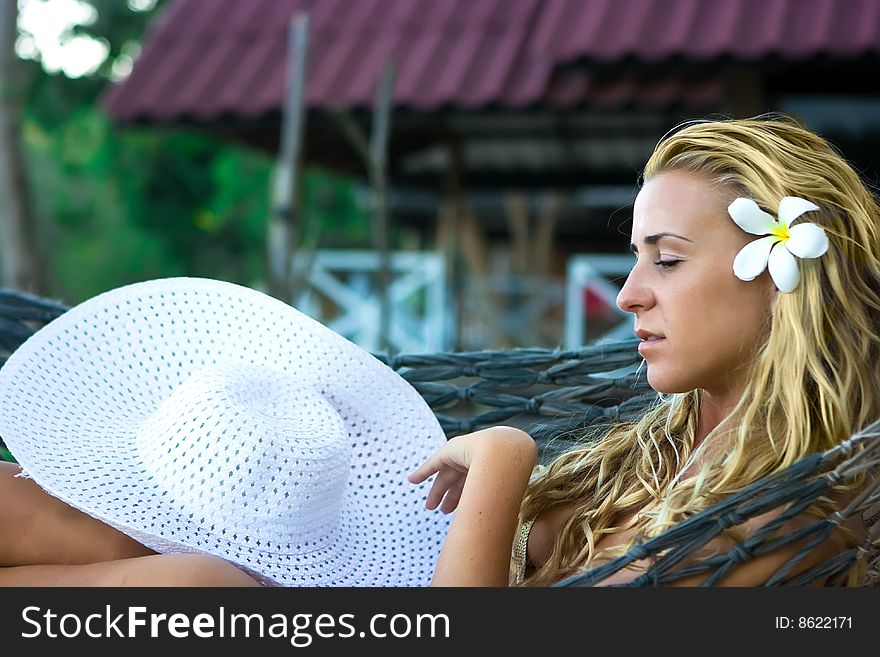 Blonde lady with white hat sitting in hammock. Blonde lady with white hat sitting in hammock