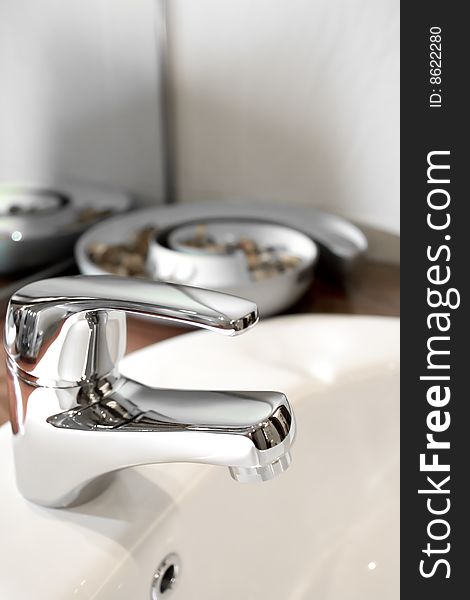 Tap of a clean washbasin with ornament on the background. Tap of a clean washbasin with ornament on the background