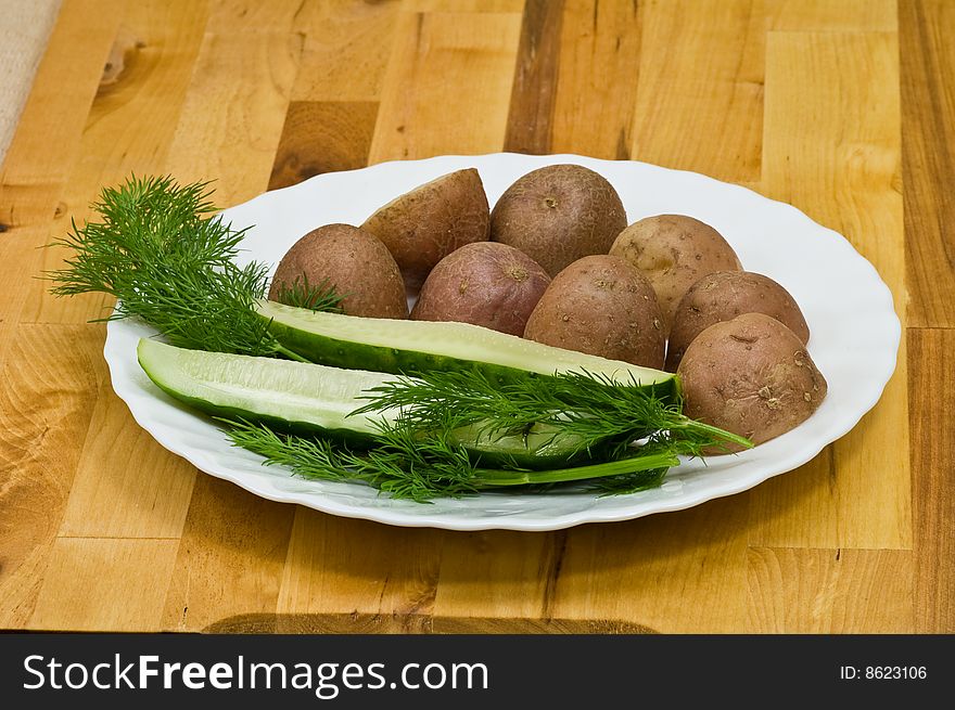 Provincial still-life with boiled potatoes, sliced salt cucumber and some dill on white porcelain  plate. Provincial still-life with boiled potatoes, sliced salt cucumber and some dill on white porcelain  plate