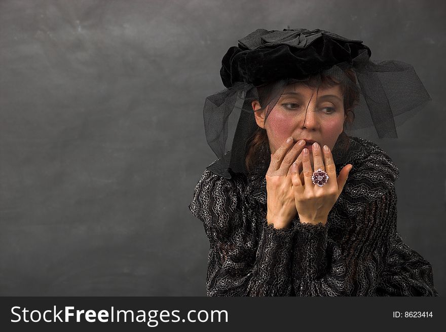 The woman in black clothes with a thoughtful sight at a grey background. The woman in black clothes with a thoughtful sight at a grey background.