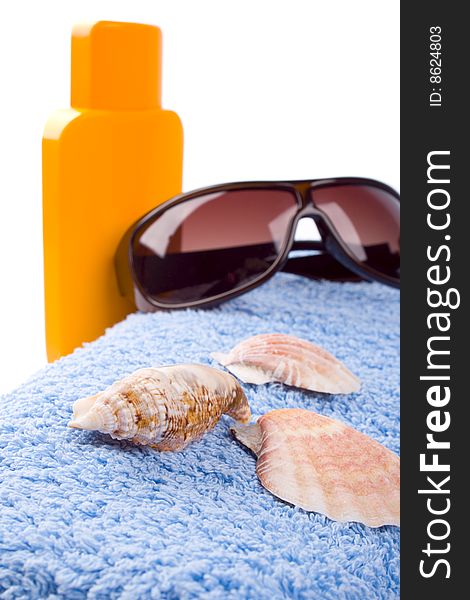 Towel, shells, sunglasses and lotion closeup on white background