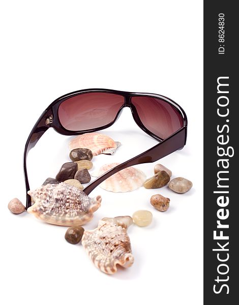 Sunglasses, shells and pebbles closeup on white background