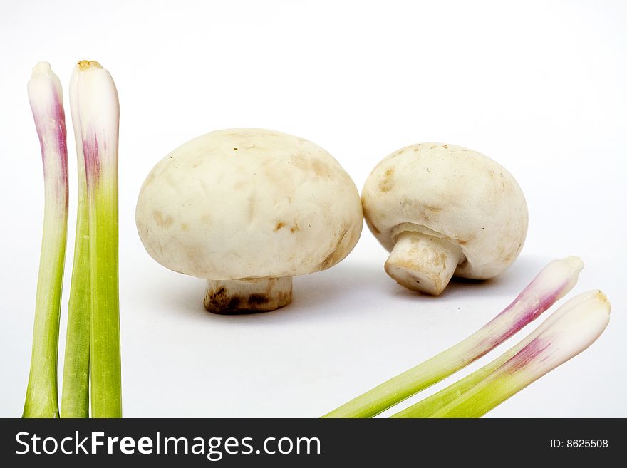 Two white mushrooms and some onions on white background. Two white mushrooms and some onions on white background.