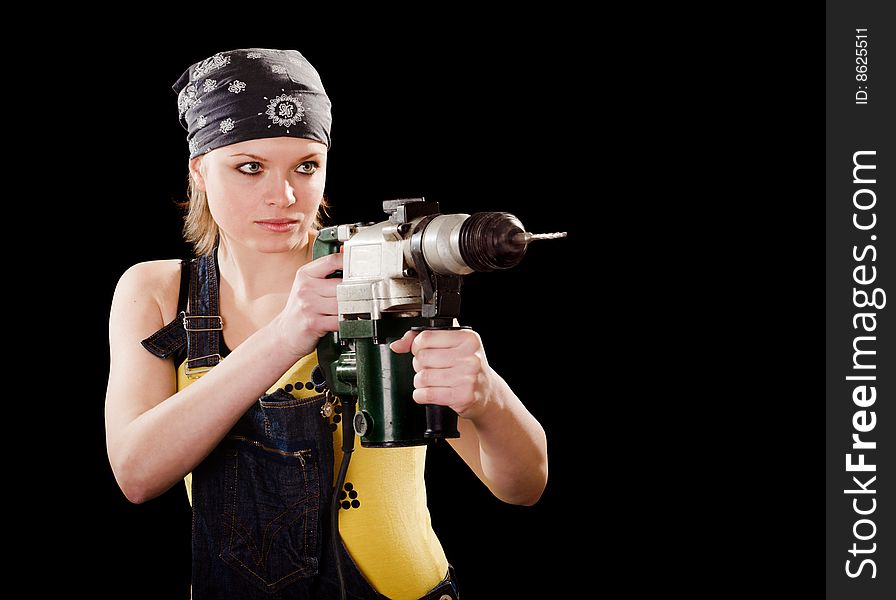 Severe young woman with a drill on black background