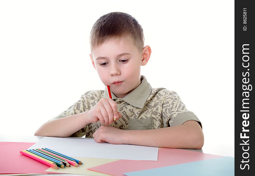 6 year old boy draws pencils sitting for a table. 6 year old boy draws pencils sitting for a table