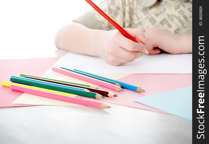 Boy draws pencils sitting for a table. Boy draws pencils sitting for a table