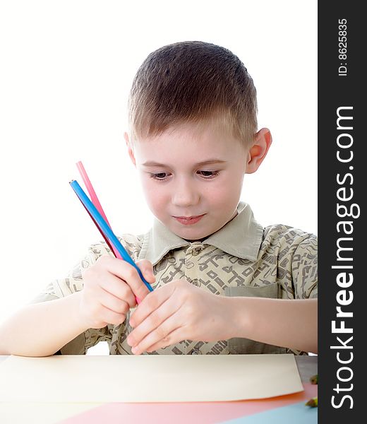 6 year old boy draws pencils sitting for a table. 6 year old boy draws pencils sitting for a table