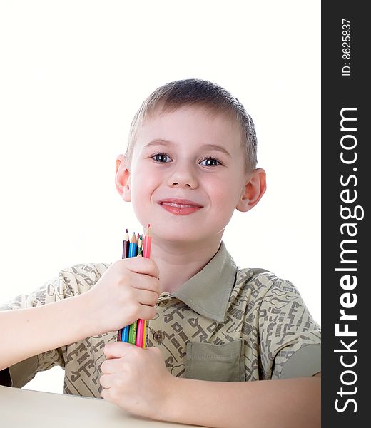 6 year old boy draws pencils sitting for a table. 6 year old boy draws pencils sitting for a table