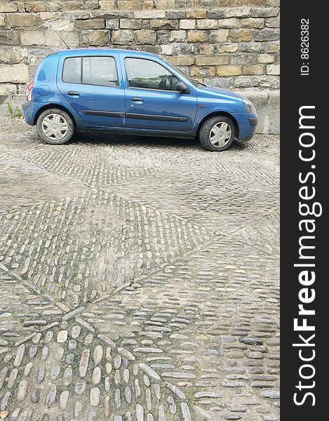 Blue car parked on a cobbled street