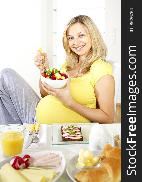 Young pretty pregnant woman sits at the breakfast table. Young pretty pregnant woman sits at the breakfast table