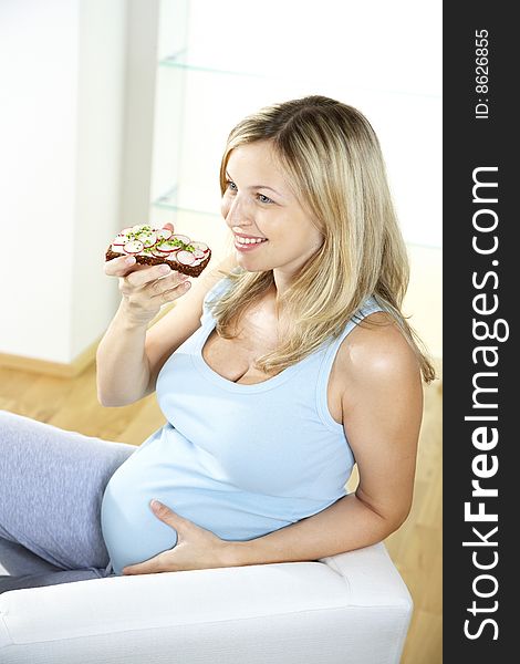 Pregnant woman eats wholemeal bread with radishes