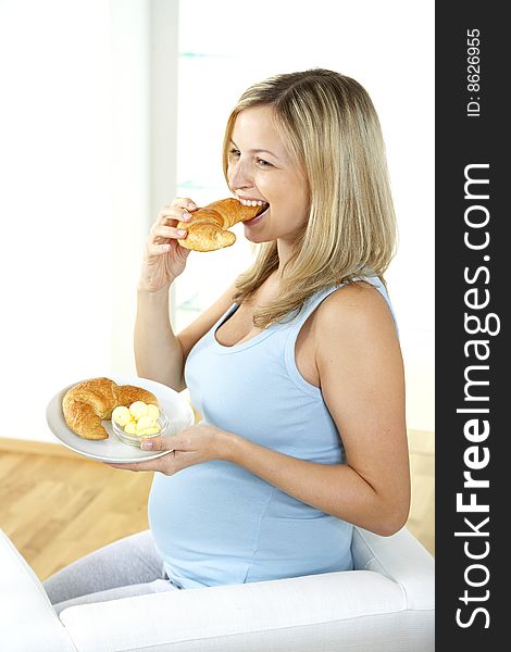 Young, beautiful, pregnant women is eating croissant. Young, beautiful, pregnant women is eating croissant