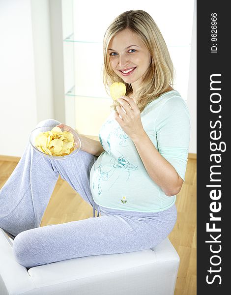 Beautiful, young, pregnant woman is eating potatoe chips. Beautiful, young, pregnant woman is eating potatoe chips