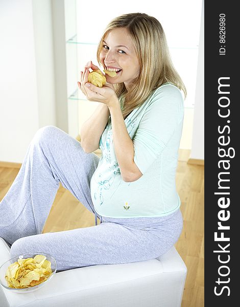 Beautiful, young, pregnant woman is eating potatoe chips. Beautiful, young, pregnant woman is eating potatoe chips