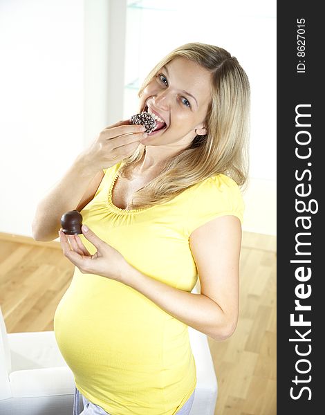 Young, beautiful pregnant woman is eating chocolate bombs. Young, beautiful pregnant woman is eating chocolate bombs