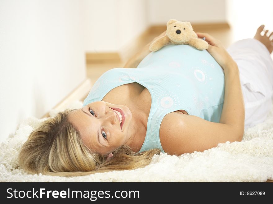 Pregnant woman keeps teddy on her belly. Pregnant woman keeps teddy on her belly