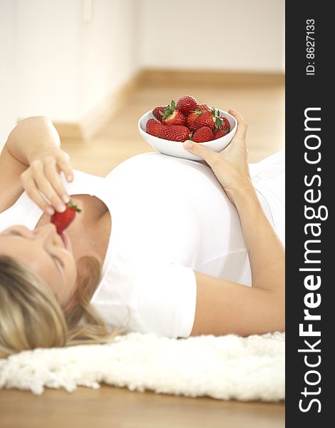 Young pretty pregnant woman eats strawberries