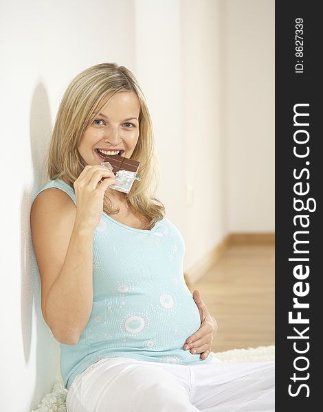 Young beautiful pregnant woman eats chocolate. Young beautiful pregnant woman eats chocolate