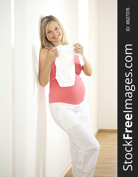 Young beautiful pregnant woman with baby clothes