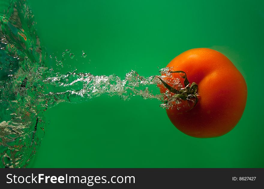 Tomato in water on a green background