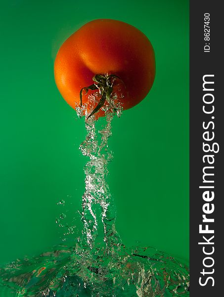 Tomato in water on a green background
