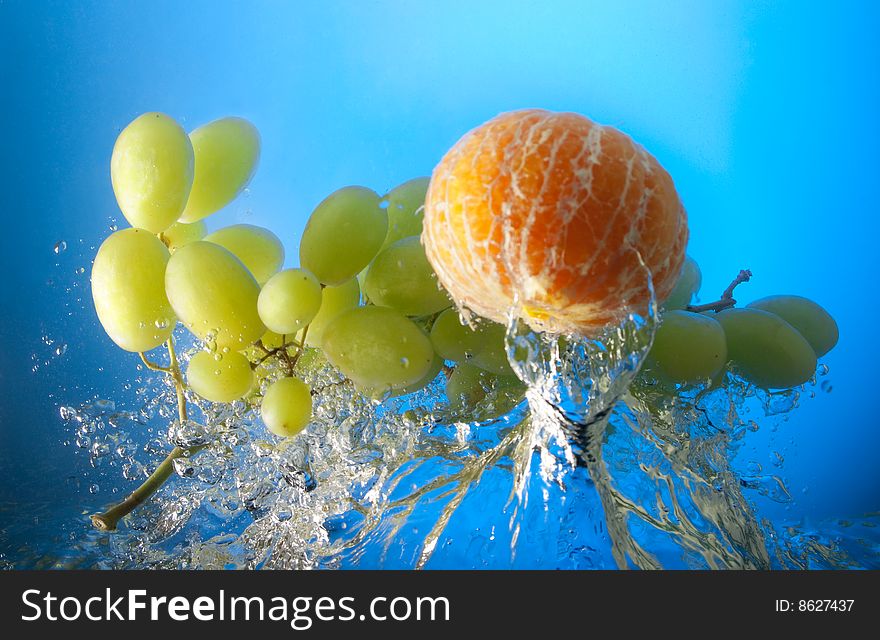 Orange and grapes in water, on a blue background. Orange and grapes in water, on a blue background