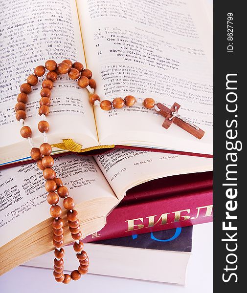 Open Holy Bible lying on stack of old books with glasses, cross and beads. Open Holy Bible lying on stack of old books with glasses, cross and beads