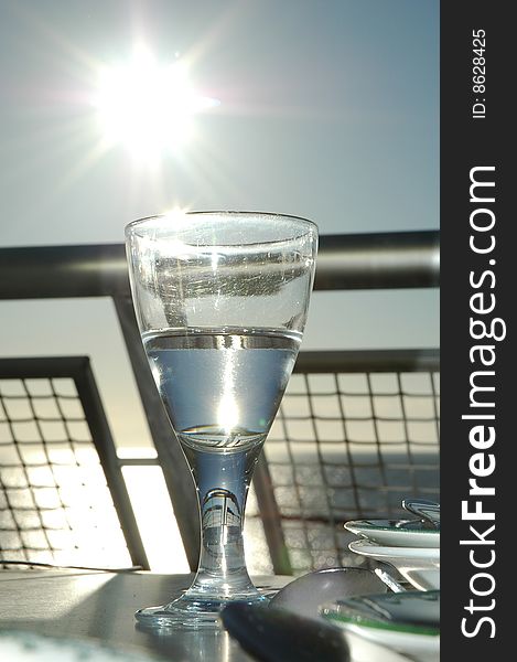 Glass of water on balcony, the sun is shining on the left.