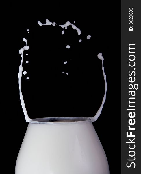 Splash milk in the glass on the black background