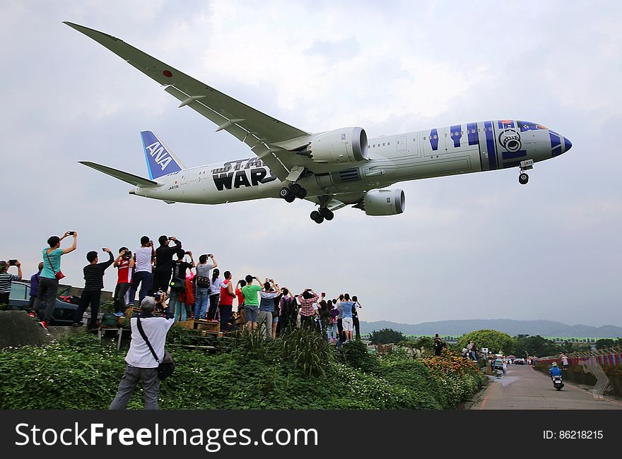 An All Nippon Airways plane with Star Wars design landing with spectators looking at it. An All Nippon Airways plane with Star Wars design landing with spectators looking at it.