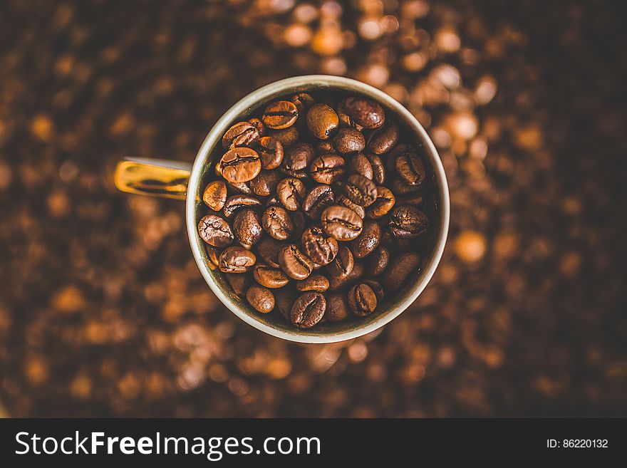 Overhead view of dry roasted beans in cup of coffee with textured brown background,. Overhead view of dry roasted beans in cup of coffee with textured brown background,