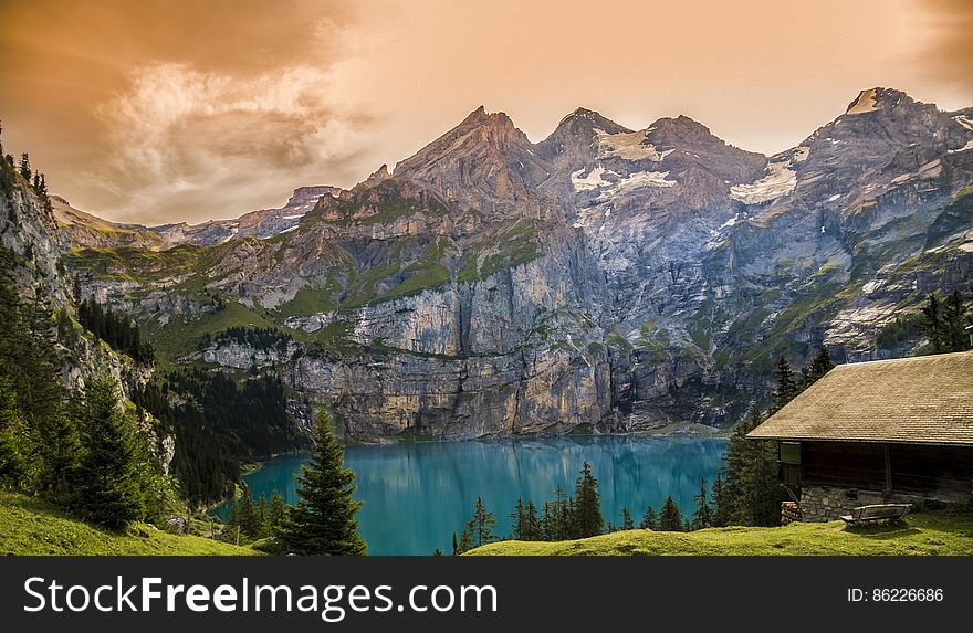 Exterior of rustic house on waterfront of alpine lake with orange skies. Exterior of rustic house on waterfront of alpine lake with orange skies.