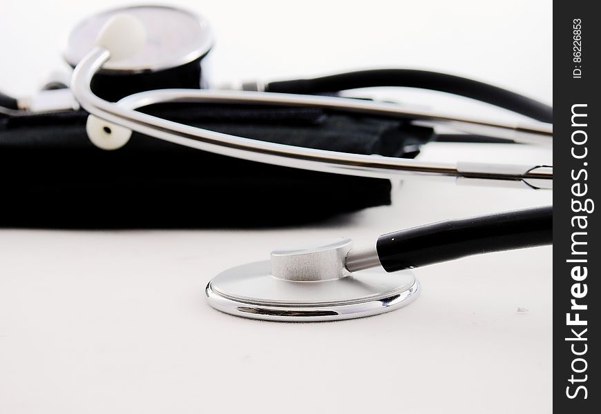 Stethoscope and blood pressure cuff on white studio background.