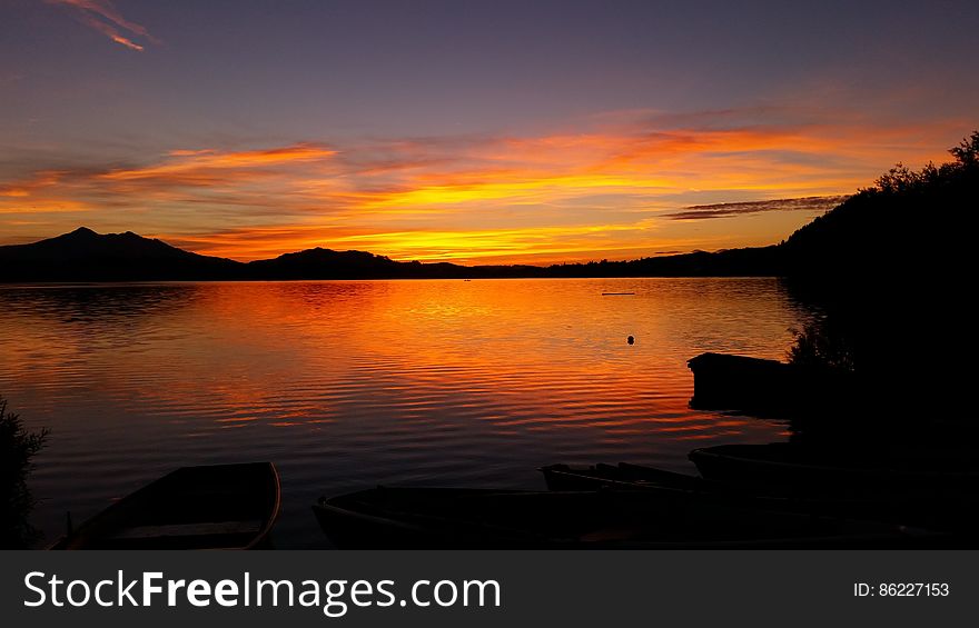 Sunset reflecting in lake along waterfront with clouds. Sunset reflecting in lake along waterfront with clouds.