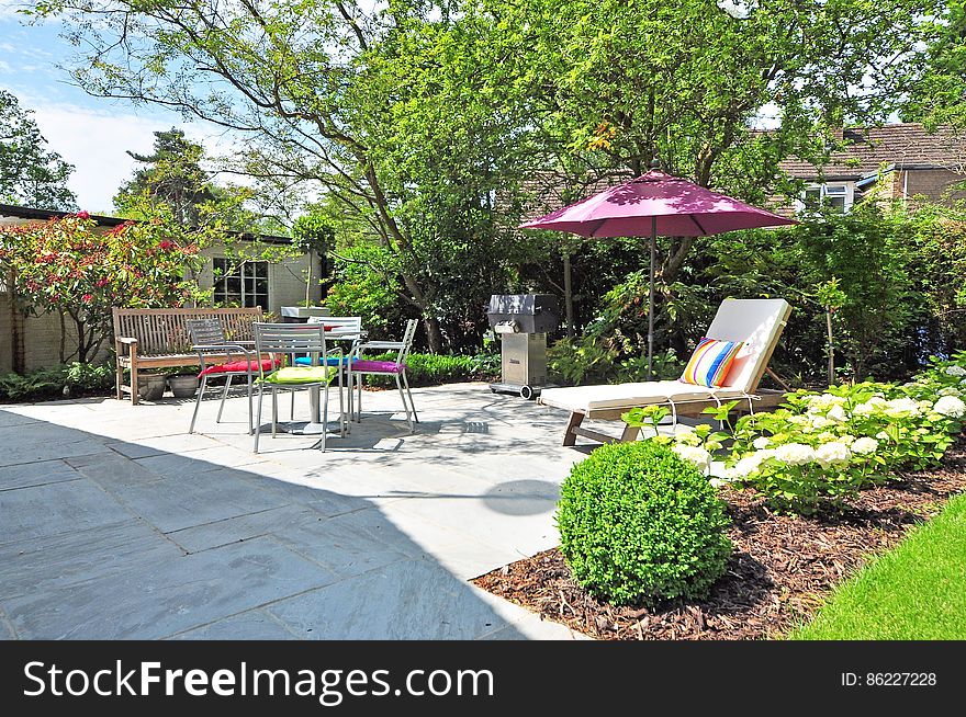 Summer garden furniture with sun-lounger and parasol in house garden. Summer garden furniture with sun-lounger and parasol in house garden.