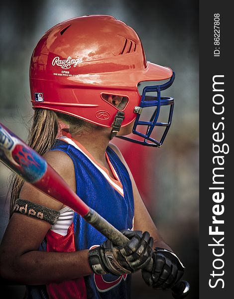 A portrait of a young girl with bat and helmet playing baseball. A portrait of a young girl with bat and helmet playing baseball.