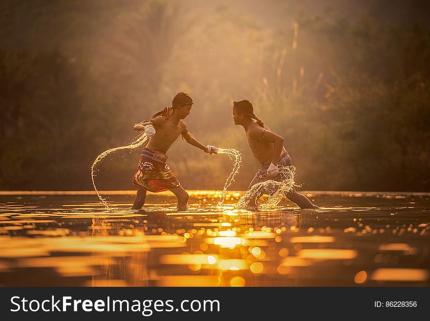 Young boys splashing and playing in water at dawn. Young boys splashing and playing in water at dawn.