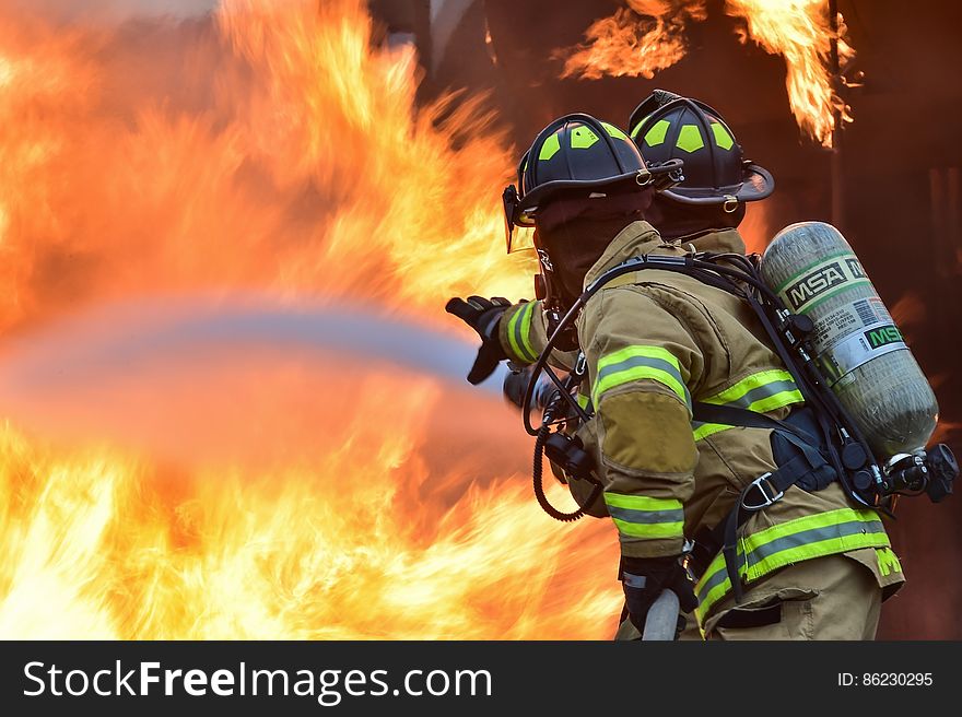 Two firemen putting out blazing fire. Two firemen putting out blazing fire.