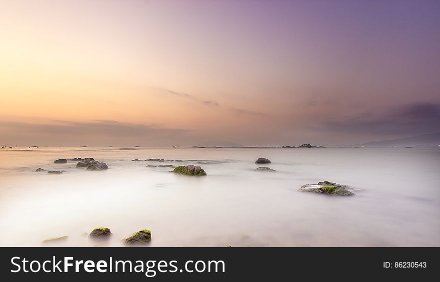 Scenic view of rocky landscape shrouded in fog at sunset.