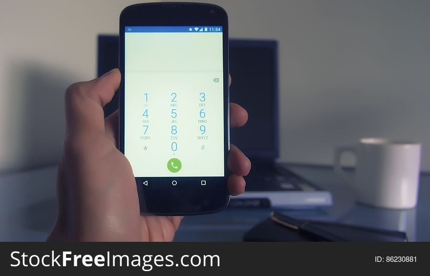 Hand of person using android smartphone at home showing numbers on screen.