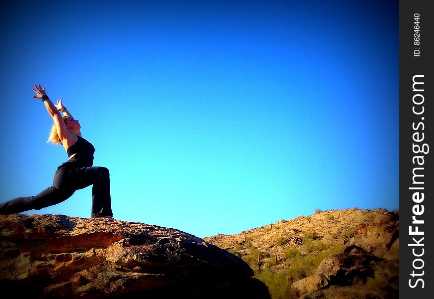 A woman outdoors doing yoga on a rock. A woman outdoors doing yoga on a rock.
