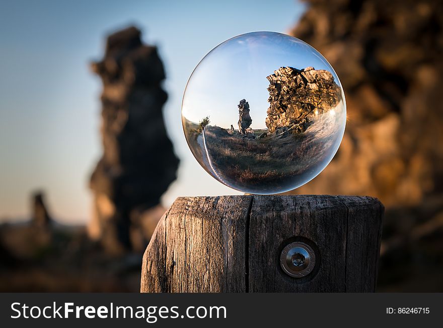 A sphere of glass on a wooden pole showing a focused image if a landscape. A sphere of glass on a wooden pole showing a focused image if a landscape.